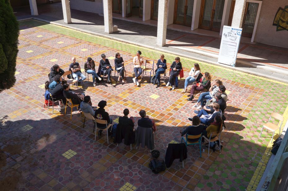 Groupe d'étudiant.e.s assis en cercle au milieu d'une cour